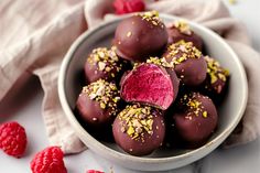 a white bowl filled with chocolate covered raspberries