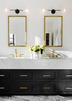 a bathroom with two sinks and mirrors on the wall next to each other in gold trimmings