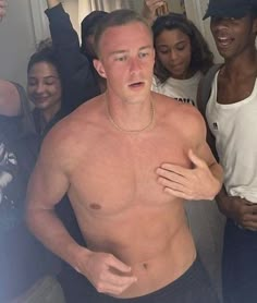 a man with no shirt standing in front of a group of people