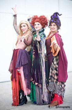 three women dressed in costume posing for the camera with one holding her hand up to the side