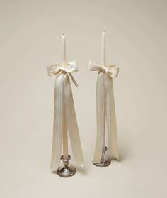 two candles with bows on them are next to each other