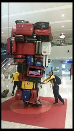 luggage stacked on top of each other in an airport baggage claim area with people walking by