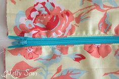 the zipper is closed on top of the flowered fabric, which has been stitched together