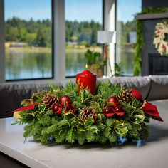 a christmas centerpiece with pine cones, holly and red berries