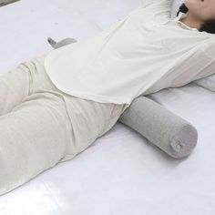 a man laying on top of a white bed next to a pillow and remote control