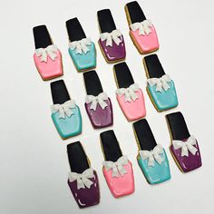 decorated cookies in the shape of nail polishes with bows on them are arranged in rows