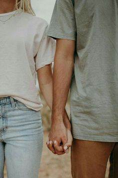 a man and woman holding hands while standing next to each other