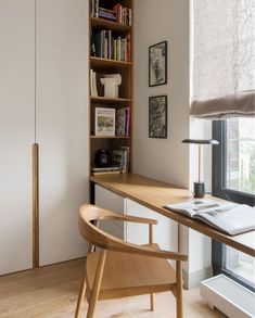 a room with a desk, chair and bookshelf next to a large window