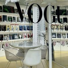 there is a table and chairs in the room with books on the wall behind it