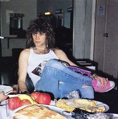 a woman sitting in front of a table filled with fruit and pastries on it