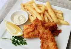 fish and fries on a white plate with lemon wedges