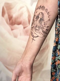 a woman's arm with a tattoo on it and a cross in the middle