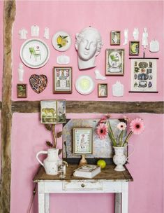 a room with pink walls and various pictures on the wall, including a white busturine