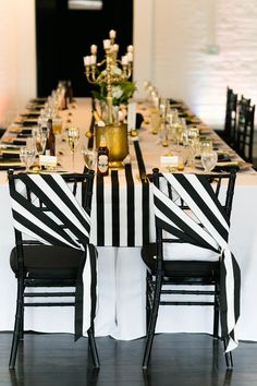 a long table with black and white striped chairs is set up for a formal dinner