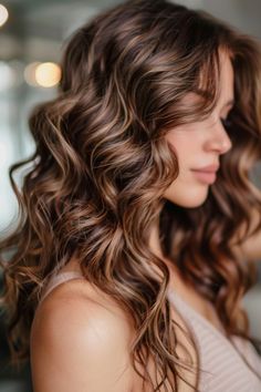 Woman with long, wavy brown hair smiling softly. Brown Hair With Gold Highlights, Brown Hair Gold Highlights, Cinnamon Highlights On Brown Hair