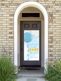 a black door with a baby shower sign on it's side and plants in front