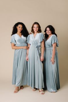 three women in blue dresses posing for the camera