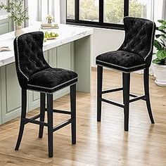 two black velvet bar stools in front of a kitchen counter with white counters and windows