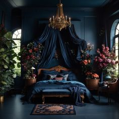 a bed with blue sheets and pillows in a dark room next to two large windows