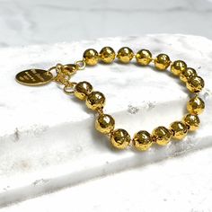 Carefully hammered by hand, our 8mm Hammered Beads bracelet embodies the gorgeous artisan style Italy is famous for. Combined with the classic shape and chic size, this bracelet stands the test of time. It is a statement piece you will want to wear for years to come. Bracelet in 925 silver with DelBrenna's 24k Yellow Gold Finish. 6 3/4” plus 1 1/4” extension. Swivel clasp. Delbrenna medallion certifies quality Italian craftsmanship. Classic Hammered Bracelets For Gift, Classic Hammered Bracelets For Gifts, Classic Hammered Bracelets As Gift, Luxury Faceted Beads Bracelets As Gift, Luxury Faceted Beads Bracelets For Gifts, Luxury Hammered Bracelets As Gift, Luxury Hammered Bracelets For Gift, Luxury Hammered Bracelets Gift, Luxury Adjustable Hammered Bracelets