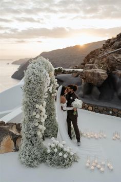 a newly married couple standing next to each other in front of an arch with candles