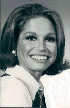 a black and white photo of a woman wearing a shirt and tie smiling at the camera