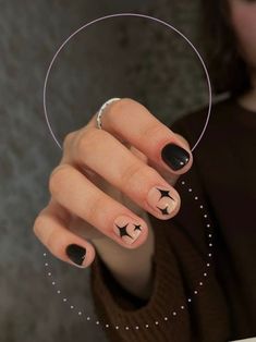 a woman's hand with black and white nail polish holding a circular object in her left hand