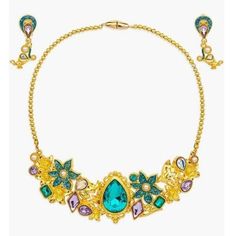 a gold necklace with green and purple stones on the front, surrounded by other jewels