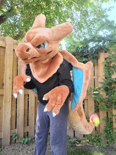 a man in a costume standing next to a wooden fence with a large stuffed animal on it's back