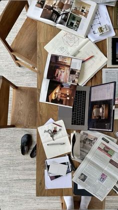 a wooden table topped with lots of papers and laptop computer sitting on top of it