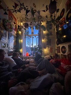 several people sitting on couches in a room with many decorations hanging from the ceiling