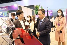 two men are talking to each other in front of some people wearing face masks and suits