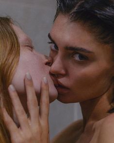 two women kissing each other in front of a mirror