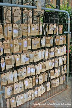 there are many bags hanging up on the wall and in front of this iron fence