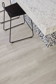 two black chairs sitting at a white marble dining table with an intricate pattern on it