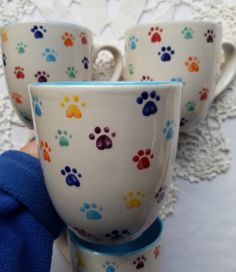 three white cups with colorful paw prints on them