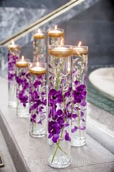 purple flowers in glass vases with candles