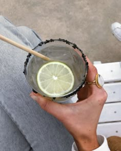 a person holding a glass with a lemon in it and a wooden stick sticking out of it