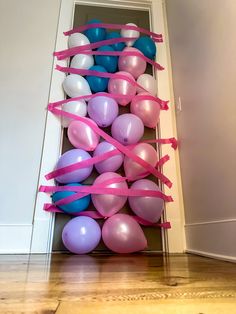 balloons tied to a wall with pink and blue ribbons