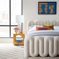 a white bed sitting in a bedroom on top of a carpeted floor next to a window