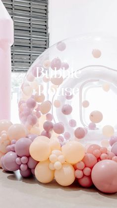 some balloons are floating in the air near a bubble house sign and pink water bottle