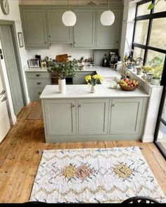 a kitchen with an area rug on the floor and green cabinets in the back ground