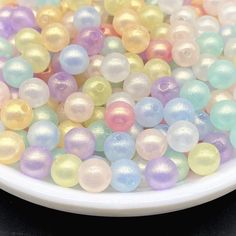 a white plate filled with lots of different colored beads on top of a black table