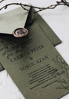 an envelope with a wax stamp on it is sitting next to some branches and leaves