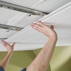 two hands are reaching up to pull the curtain from the ceiling in preparation for installation