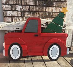 a wooden toy truck with a christmas tree on the back and wheels, sitting on a wood deck