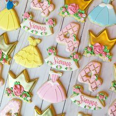 some decorated cookies are laying on a white wooden surface with pink and yellow decorations around them