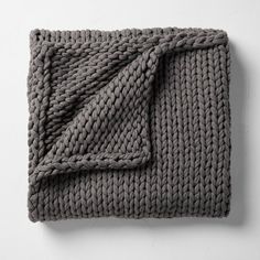 a gray blanket folded on top of a white wall