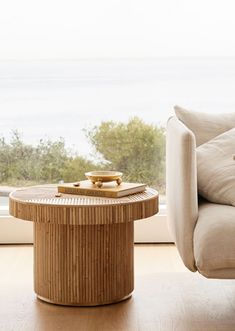 a couch and table in front of a window with the ocean out to the side