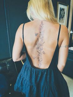 the back of a woman's dress with tattoos on her upper and lower back